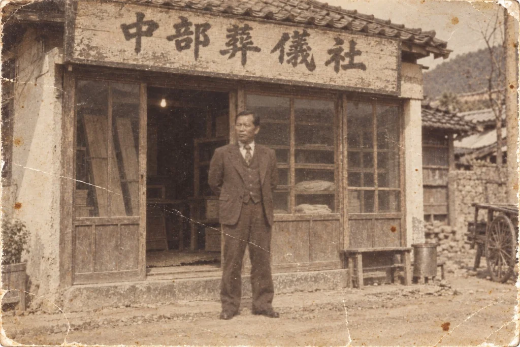 1960년대 충청북도 음성, 창업주가 장의사 앞에 선 모습 (당시 자료를 바탕으로 복원한 사진)